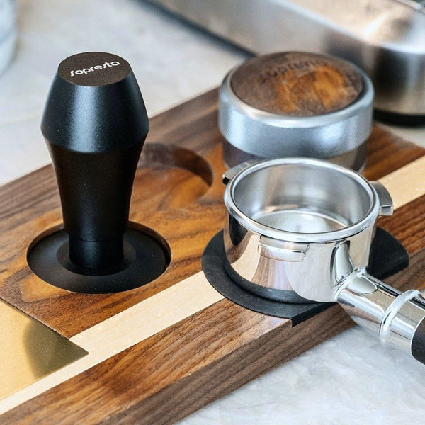 Sopresta-tamper, fördelare och portafilter på en tamperstation i valnöt
