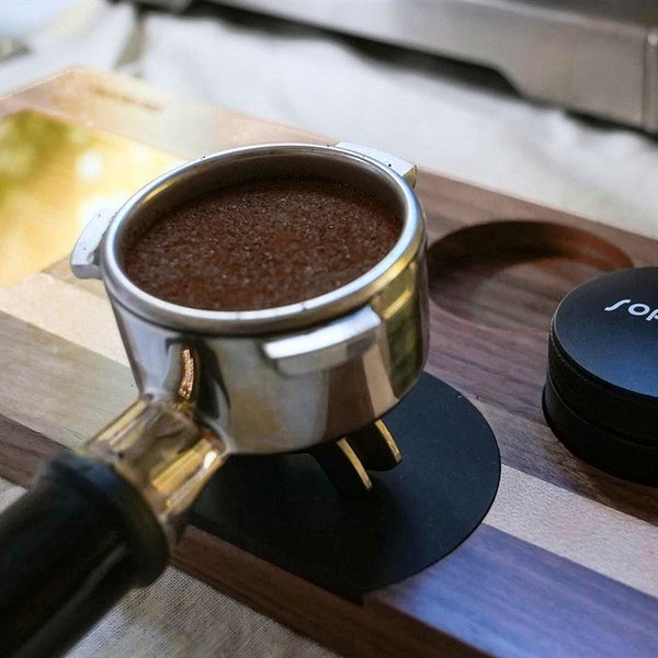 Ett portafilter med kaffe vid en Sopresta-tampermatta